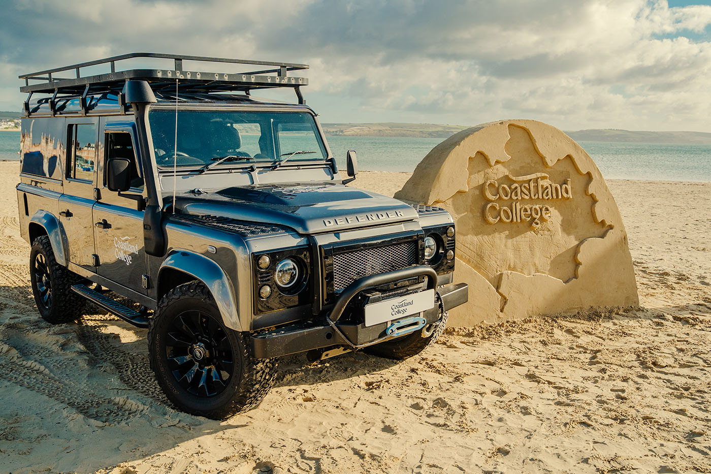 photo of a coastland college range rover next to a coastland college sand structure